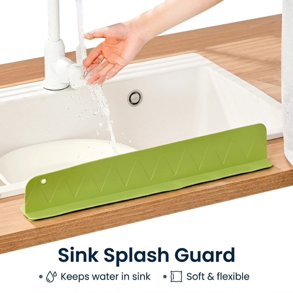 Green sink splash guard on a wooden countertop with a hand washing under running water.