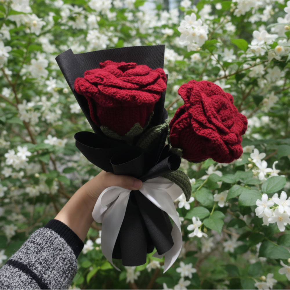 Bouquet of red crocheted roses held by a person against a plain background